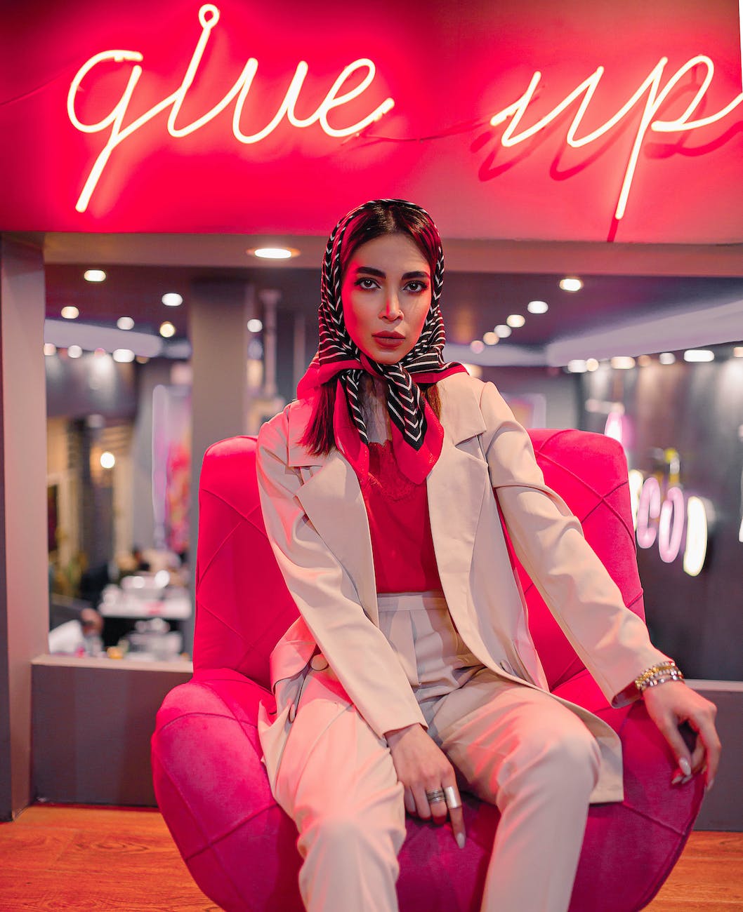 a woman in a blazer sitting on a pink chair